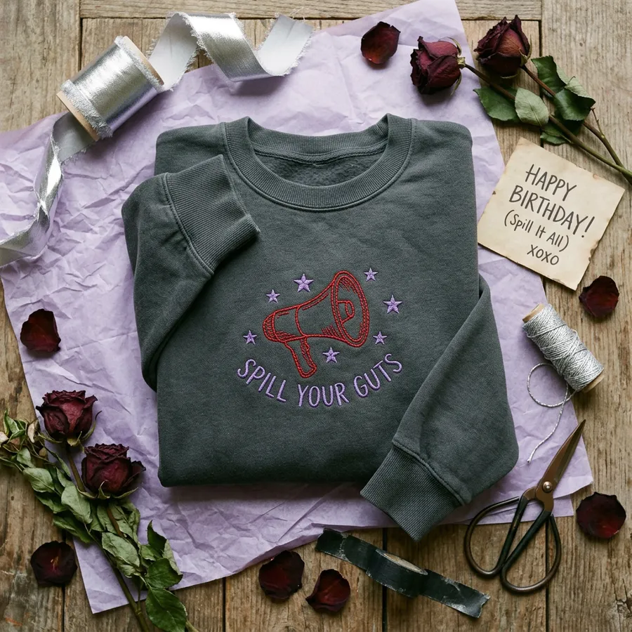 Styled flat lay of the Spill Your Guts embroidered sweatshirt with concert tickets and friendship bracelets